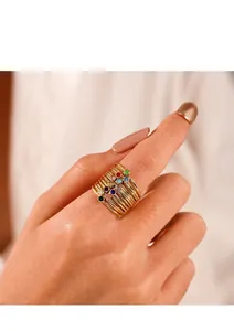 Stacked gold titanium rings featuring vibrant multicolored zircons worn on finger