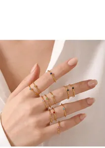 Detail of stacked minimalist gold rings with vibrant colorful gemstones on fingers