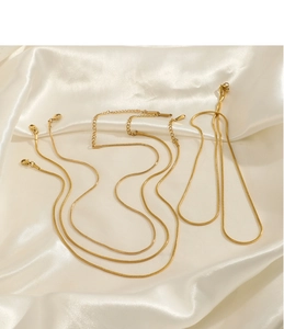 Détails de chaînes serpent dorées avec fermoirs mousquetons sur tissu en soie blanche