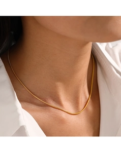 Gros plan d'un collier chaîne serpent dorée porté par un mannequin avec chemise