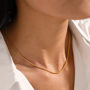 Collier maille serpent doré minimaliste pour femme porté sur le cou avec chemise blanche