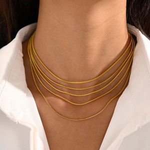 Collier élégant à plusieurs rangs en maille serpent dorée porté par un mannequin