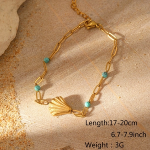 Detail eines Gold-Muschelanhängers mit türkisen Perlen auf Strandsteinhintergrund