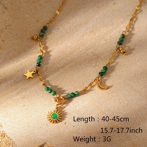 Detailaufnahme einer goldenen Boho-Halskette mit Sonnenanhänger und grünen Perlen