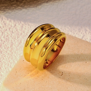Détail macro d'une bague vague dorée à trois couches sur socle en pierre poli