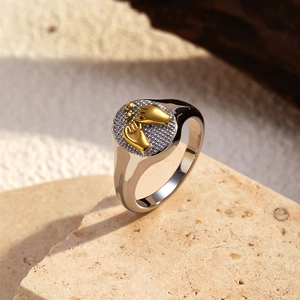 Macro shot of two-tone 18k gold plated ring with hand-holding motif and baby footprints