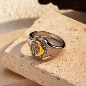 Silver signet ring with gold crescent moon and stars on a natural stone background