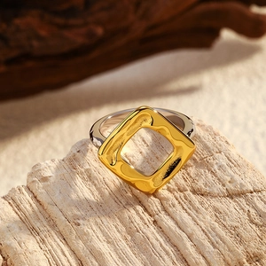 Détail d'une bague bicolore en acier avec texture martelée dorée sur du bois