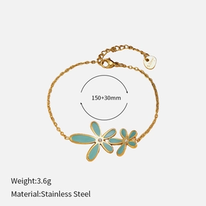Détail d'un bracelet en acier inoxydable doré avec fleurs en émail bleu et strass