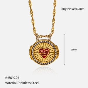 Détail d'un pendentif pièce en acier doré avec cœur rouge et pierres de zircone