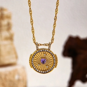 Détail du pendentif doré avec cœur violet et cristaux sur une chaîne torsadée dorée