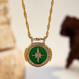 Détail d'un collier chaîne torsadée dorée avec pendentif étoile en émail vert et zircons