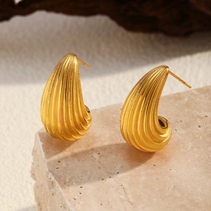 Detalle de pendientes de gota bañados en oro de 18K con textura acanalada sobre piedra