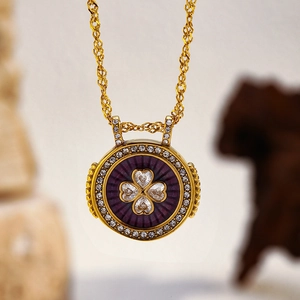 Détail macro du pendentif trèfle doré avec émail violet et pierres de zircone blanches