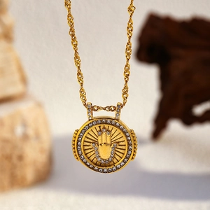 Détail du collier à chaîne torsadée dorée avec pendentif main de Hamsa et strass blancs