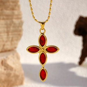 Detailed macro of gold-plated cross necklace with marquise-cut ruby red gemstones