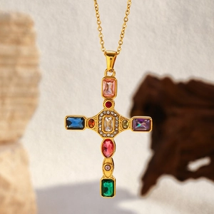 Close-up of gold plated cross necklace featuring colorful gemstones and crystal accents