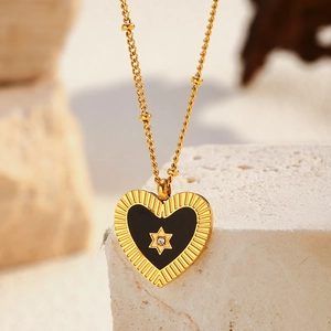 Détail macro du pendentif cœur doré avec incrustation noire et motif étoile sur pierre