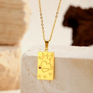 Détail macro d'un pendentif tarot doré avec étoile et lune sur un fond de pierre naturelle
