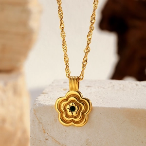 Macro d'un pendentif fleur plaqué or 18K avec zircon vert sur pierre texturée