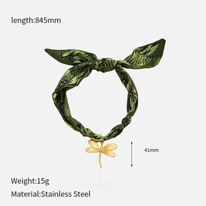 Detail showing green botanical scarf with a golden stainless steel dragonfly pendant