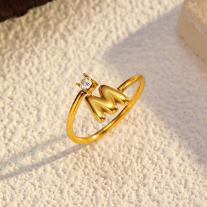 Détail macro d'une bague ouverte plaquée or 18k avec la lettre M et petit zircon
