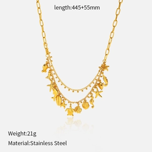 Détail macro du collier multi-rangs en acier doré avec des charms étoile de mer et coquillage