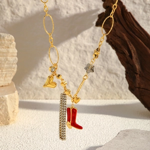 Détail du collier plaqué or 18K avec breloques cœur, étoile et botte sur fond de pierre