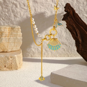 Collier marin doré avec pendentifs coquillages étoiles et perles sur décor naturel