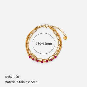 Close-up of double-layer gold stainless steel bracelet with red beads and s.steel tag