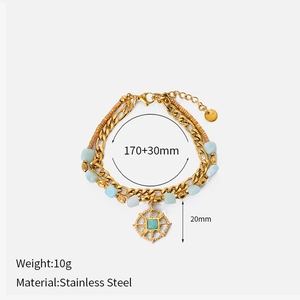 Detail of double-layer stainless steel bracelet with blue gemstone and sunburst pendant