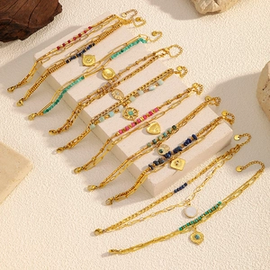 Detail of layered gold bohemian bracelets with colorful beads and symbolic charms