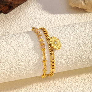 Detail of double-layer gold chain bracelet with pink gemstone beads and engraved oval pendant