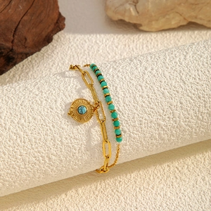 Detail of double-layer gold link chain with turquoise beads and sunburst charm