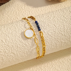 Detail of gold double-layer bracelet with white shell pendant and blue bead accents