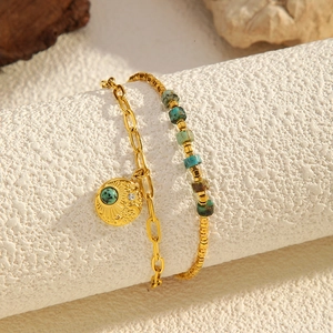 Detail of layered gold bracelet with turquoise stones and coin pendant on a display