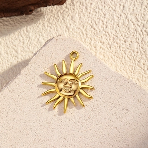 Detail eines 18K vergoldeten Sonnenanhängers mit Strahlen auf Steinhintergrund