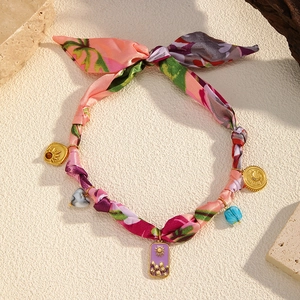 Detailed close-up of floral scarf necklace featuring elegant gold charms and colorful beads