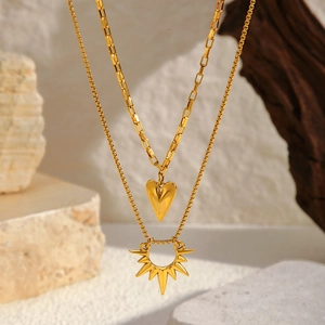 Dettaglio dei ciondoli a girasole e cuore dorati su collane in acciaio inossidabile