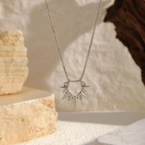 Collana con pendente a raggiera argentata su sfondo di pietra naturale e legno