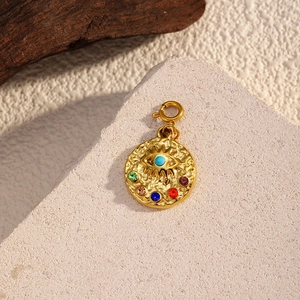 Macro di un ciondolo dorato martellato con occhio turchese e strass colorati brillanti