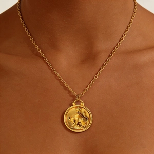 Gold Taurus zodiac coin necklace with embossed bull pendant on model's neck