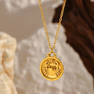 Macro shot of gold Cancer zodiac coin pendant with crab relief on stone background