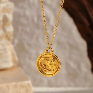Macro detail of gold zodiac pendant with engraved stars on a textured stone background