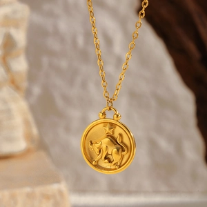 Macro shot of gold plated Taurus zodiac coin necklace with matte embossed bull detail