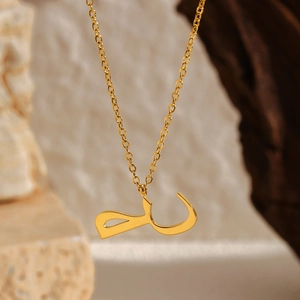 Détail d'un pendentif lettre arabe plaqué or 18 carats sur une fine chaîne à maillons