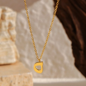 Détail macro du pendentif lettre D en or 18k sur une chaîne fine en acier inoxydable