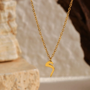 Vue macro d'un pendentif lettre arabe plaqué or 18k sur une fine chaîne en acier inoxydable