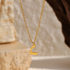 Détail du collier avec pendentif lettre arabe en or 18 carats sur fond de pierre naturelle