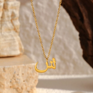 Vue macro d'un pendentif lettre arabe Shin plaqué or 18K sur chaîne acier inoxydable
